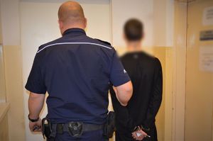 policjant prowadzi zatrzymanego
