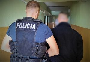 policjant doprowadza zatrzymanego