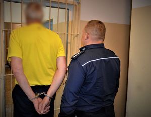 policjant doprowadza zatrzymanego