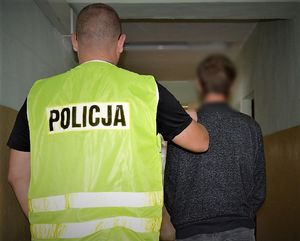 Policjant doprowadza zatrzymanego