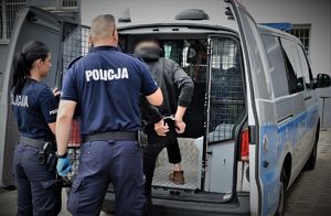 policjanci doprowadzają zatrzymanego