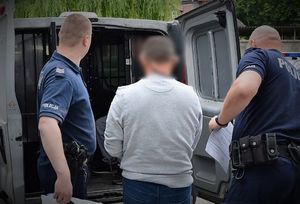 policjant doprowadza zatrzymanego