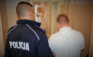 policjant doprowadza zatrzymanego