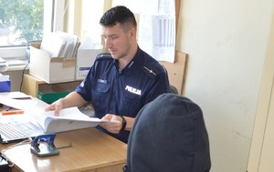 policjant doprowadza zatrzymanego