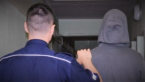 policjant doprowadza zatrzymanego