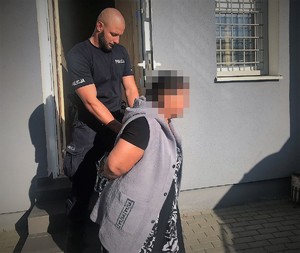 policjant doprowadza zatrzymanego