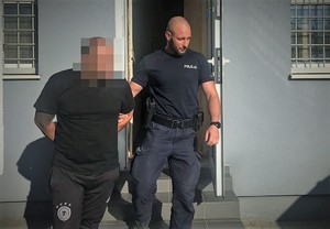 policjant doprowadza zatrzymanego