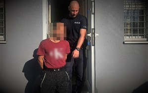 policjant doprowadza zatrzymanego